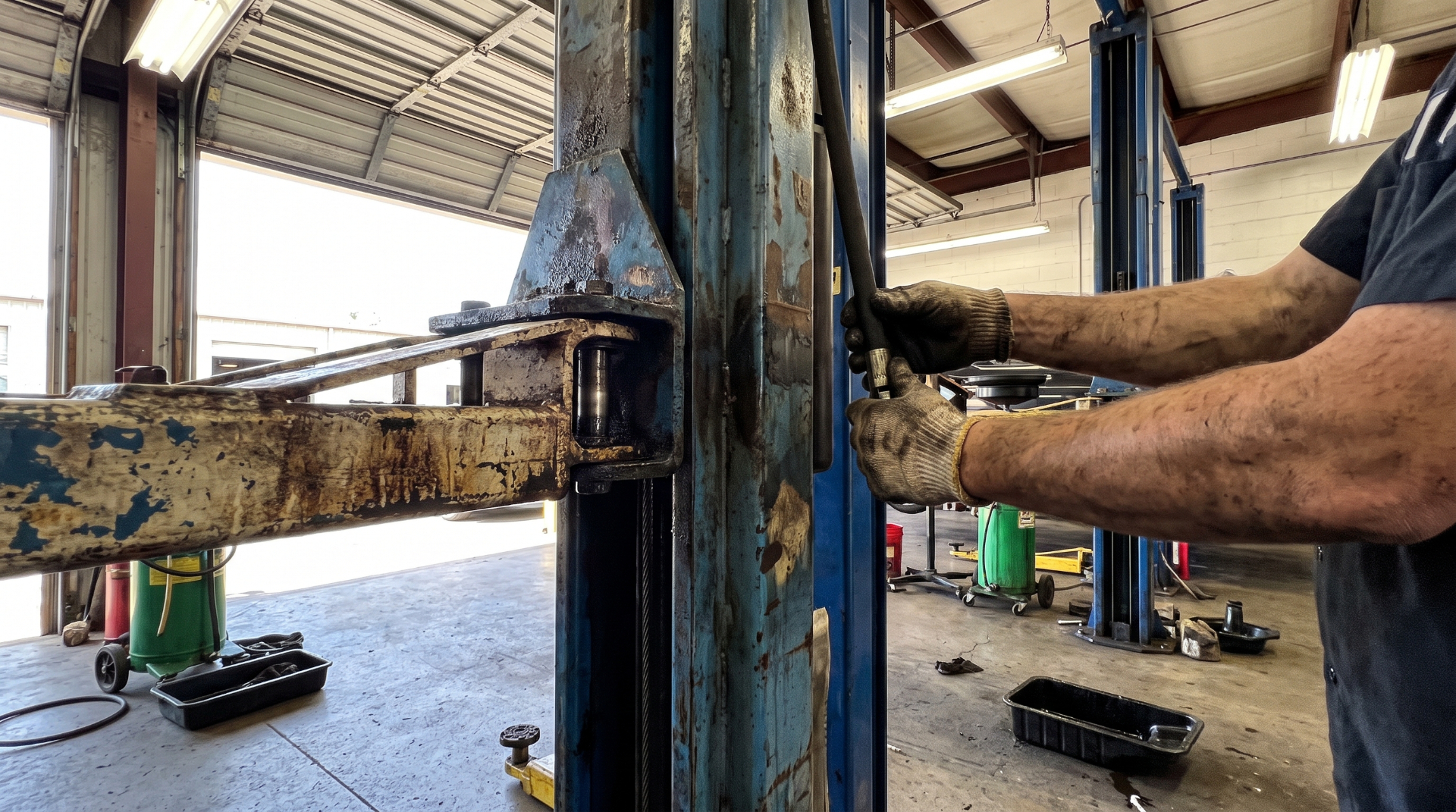 Technician replacing a hydraulic component on a two-post lift.